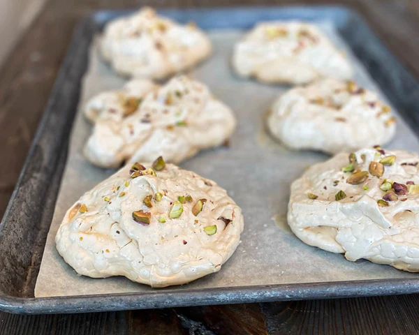Ina Garten's Salted Pistachio Meringues cooling on a parchment-lined baking sheet