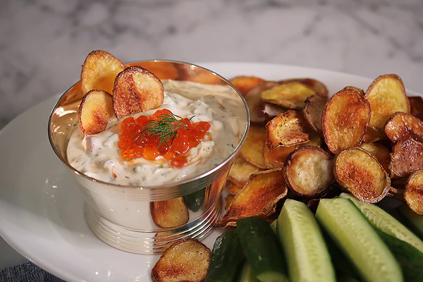 Ina Garten's caviar dip with red caviar garnish served with crispy potato wedges and cucumber slices
