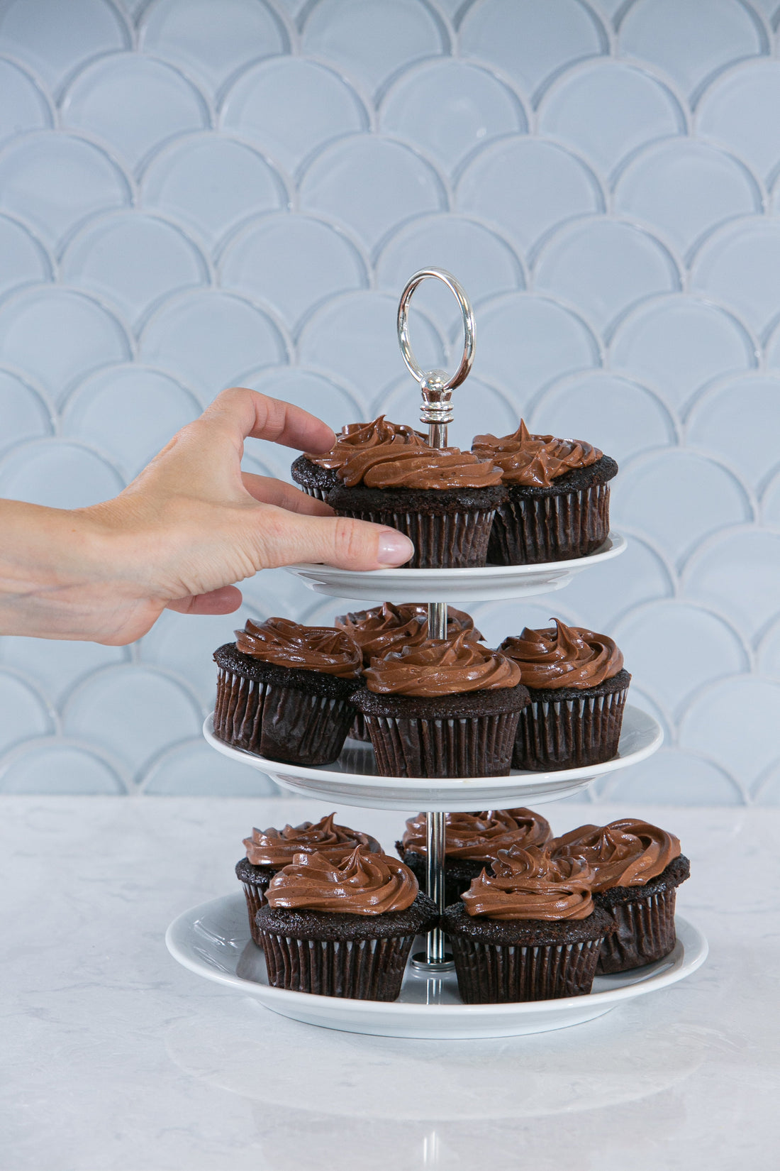 Ina Garten's Beatty's Chocolate Cupcakes with swirled chocolate frosting on a three-tier silver cupcake stand