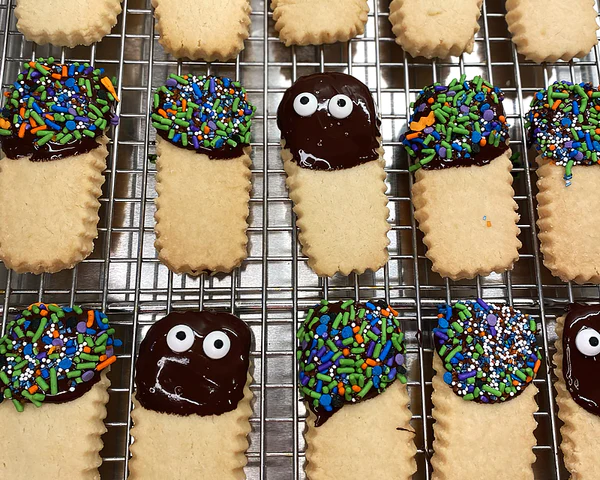 Ina Garten's Halloween shortbread cookies with chocolate icing and sprinkle faces on a cooling rack