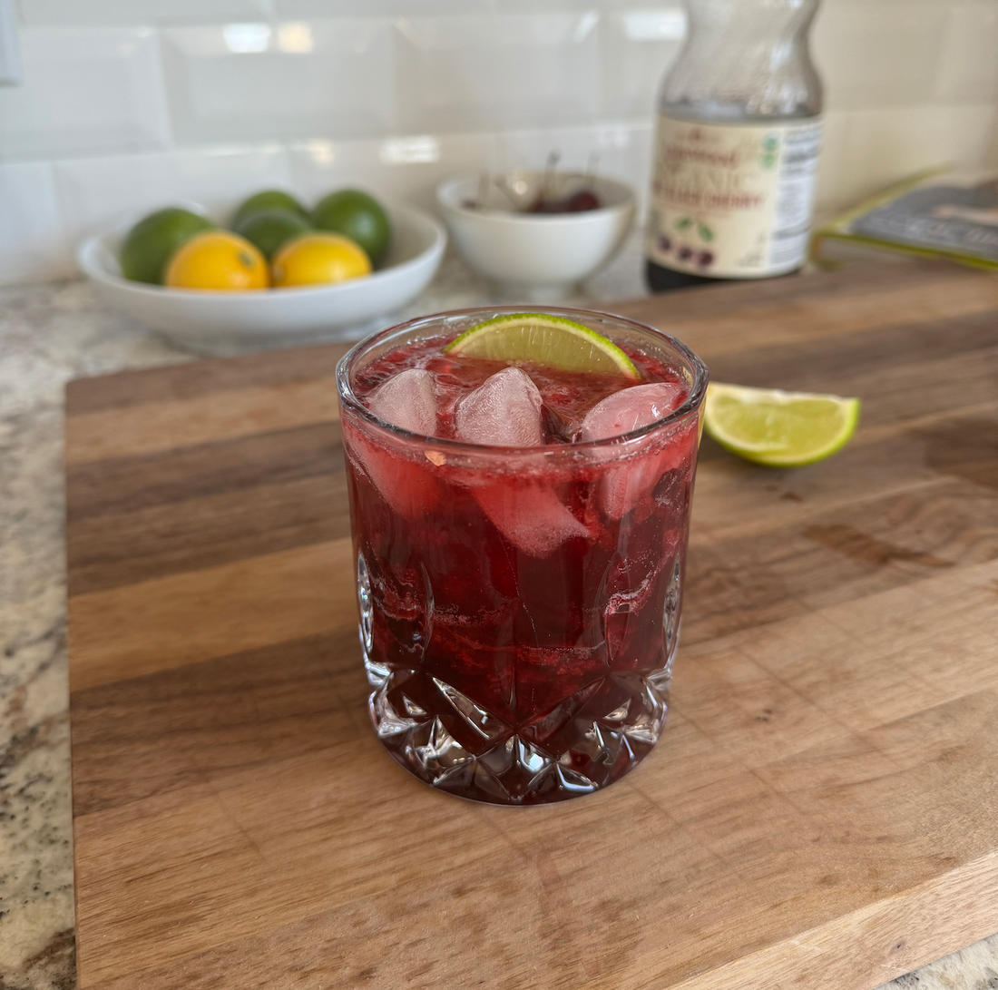 Dark Cherry Lime Mocktail in a glass with lime and cherry garnish