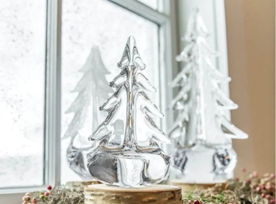 Simon Pearce mouth-blown glass evergreen tree sculptures on a shelf, timeless holiday decor