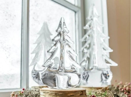 Simon Pearce mouth-blown glass evergreen tree sculptures on a shelf, timeless holiday decor