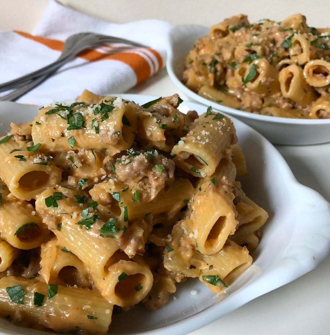 Trent's favorite rigatoni pasta with meat sauce, parmesan, and fresh herbs in two white bowls