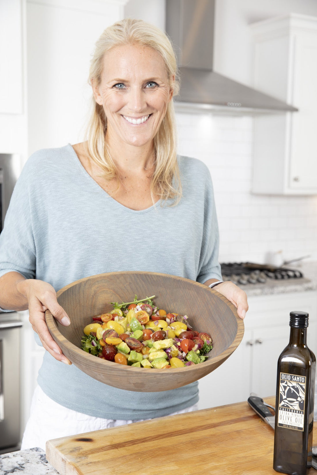 Cassandra holding a wooden bowl of Barefoot Contessa tomato and avocado salad with colorful cherry tomatoes