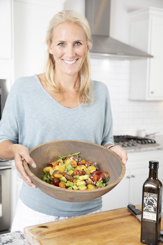 Cassandra holding a wooden bowl of Barefoot Contessa tomato and avocado salad with colorful cherry tomatoes