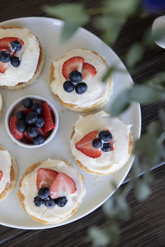 Classic yellow layer cake with lemon curd filling and fresh strawberries on a cake stand