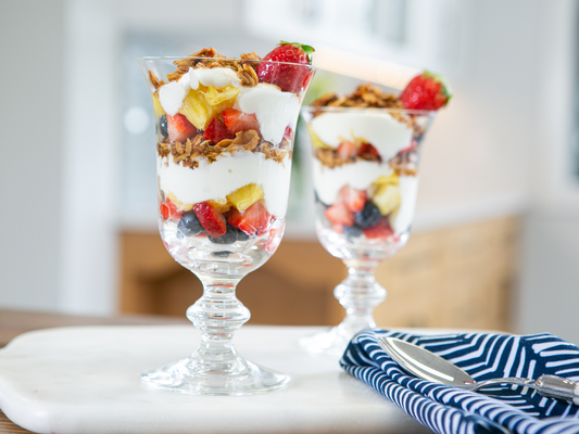 Ina Garten's Breakfast Fruit Crunch layered with yogurt, granola, and fresh berries in two stemmed glasses
