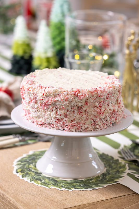 Cassandra's Candy Cane Crunch Cake coated in crushed peppermint on a white cake stand