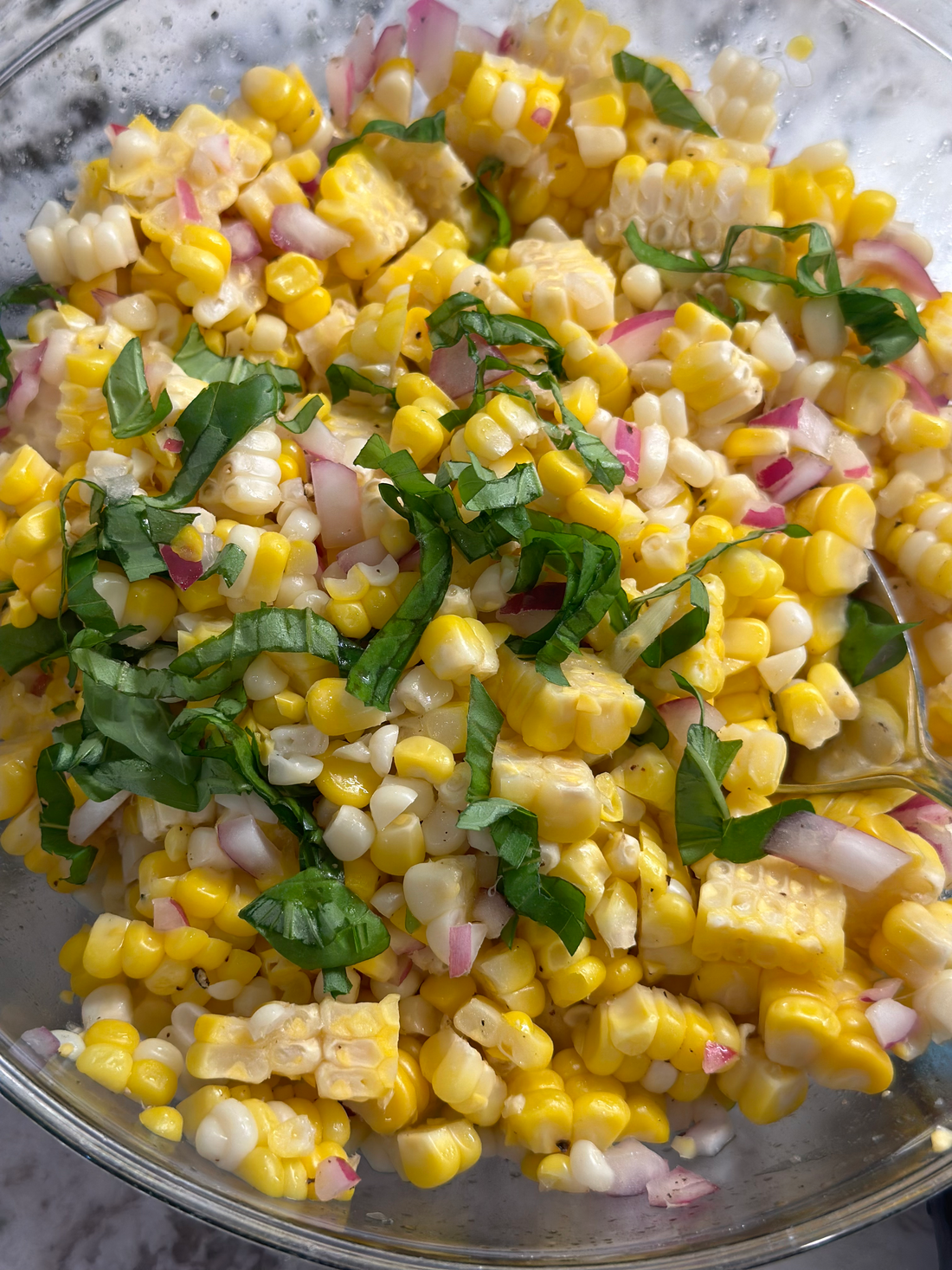 Fresh Corn Salad with cherry tomatoes, basil, and vinaigrette in a bowl