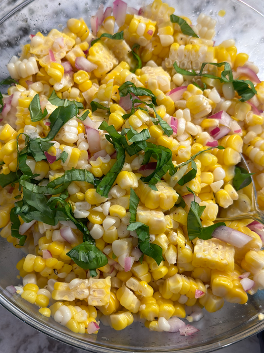 Fresh Corn Salad with cherry tomatoes, basil, and vinaigrette in a bowl
