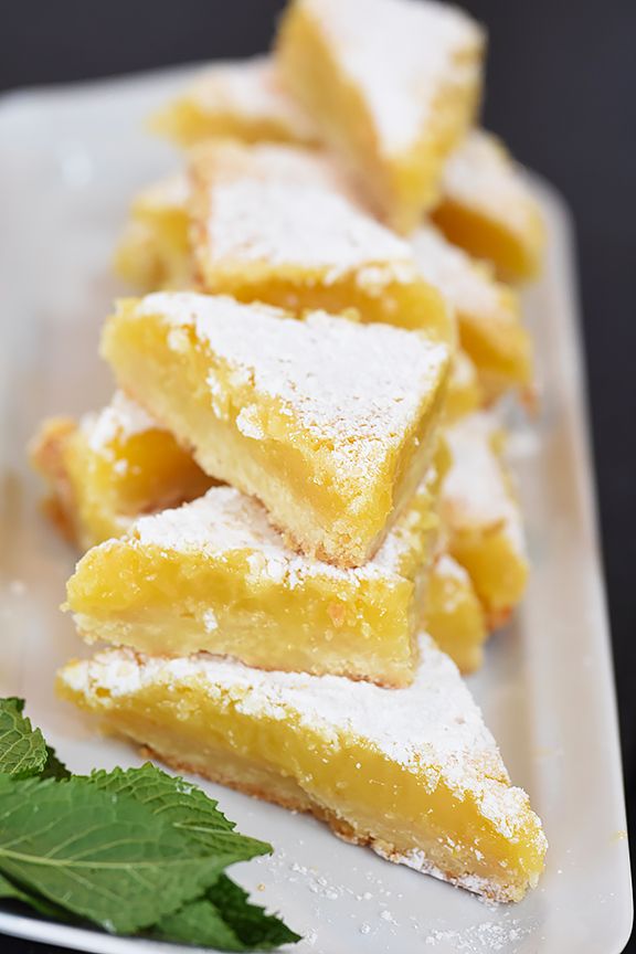 Ina Garten's classic Lemon Bars with powdered sugar dusting on a cutting board