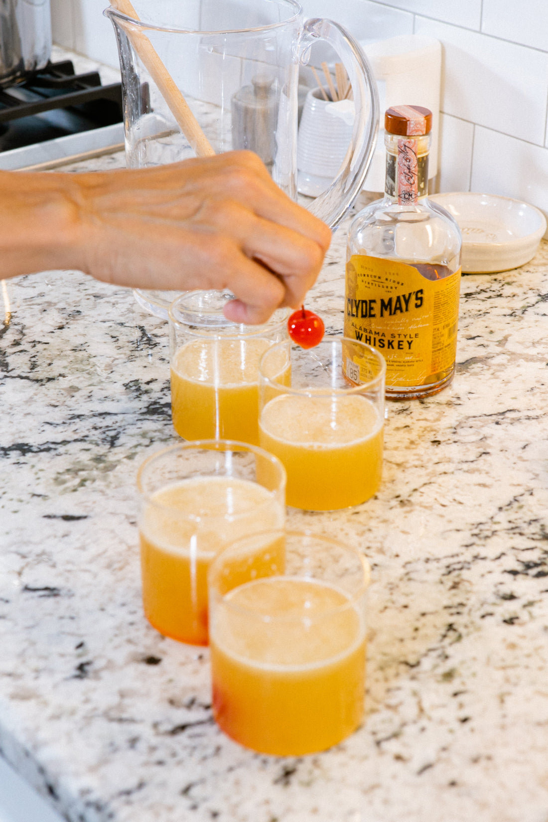 Ina Garten's Whiskey Sours with maraschino cherry garnish being prepared, Clyde May's whiskey in background