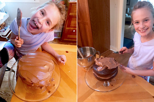 Two young girls laughing and frosting a chocolate layer cake for Cassandra's year of birthday cakes