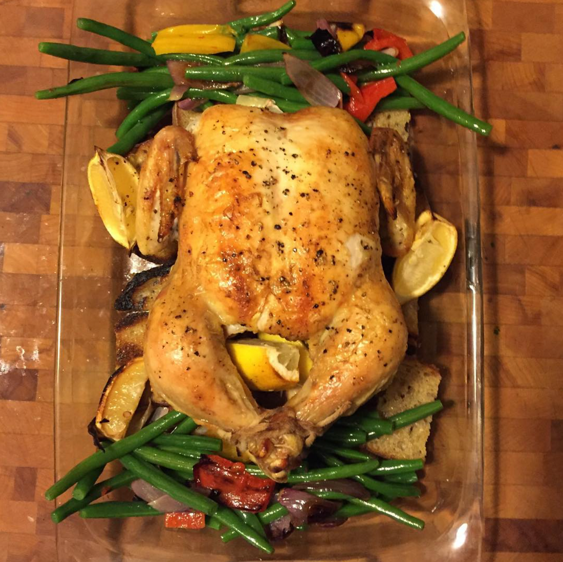 Trent from StoreBoughtIsFine's whole roast chicken with green beans, colorful peppers, and lemon in a glass roasting pan