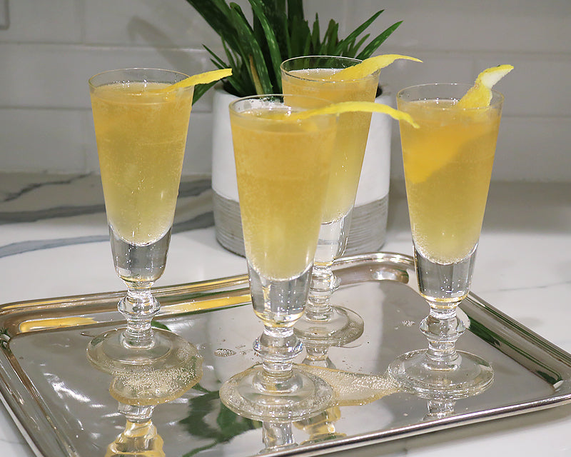 4 La Rochere Antoine Champagne Flutes with yellow cocktail garnished with lemon on a silver tray 