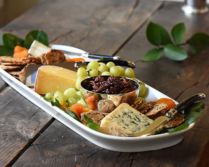 The Barn Platter sits on a wood table and is filled with cheeses, green grapes and earthy crackers