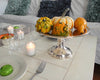 Pumpkins and guards on vintage silver stand on coffee table arrangement