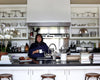 Ina Garten in her kitchen with Detailed image of HÔTEL Silver pieces behind her on shelves. Image: Béatrice de Géa for The New York Times