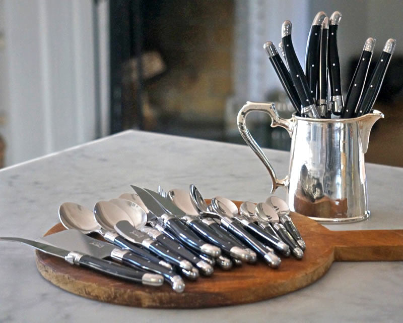 Laguiole flatware set on a cutting board and in a silver cup