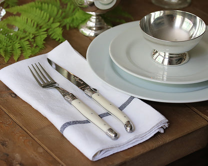 French knife and fork on a napkin next to a table setting 