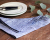 casually folded indigo linen napkin next to white dinnerware plate and everyday flatware