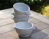 Four white porcelain classic onion soup bowls sitting on outdoor table