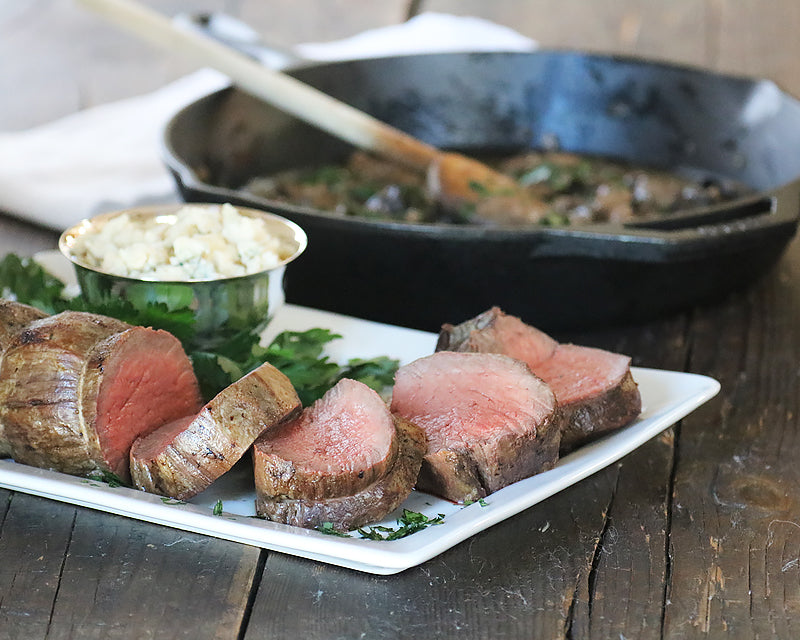 Lodge 12 inch Cast Iron Skillet sits on a dining table filled with sauteed mushrooms that pair perfectly with filet mignon.