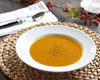 White Pillivuyt soup bowl filled with broth on round woven placemat