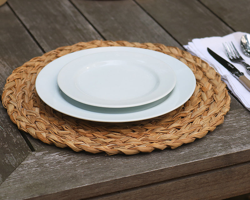 White dinner plate and salad plate stacked on round woven placemat