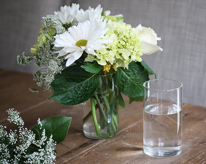 Simple water glass filled with fresh-cut flowers