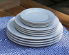 Pillivuyt white dinner plates, salad plates, and dessert plates stacked on striped placemat
