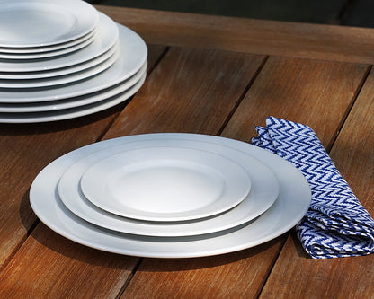 White dinner plates stacked on a wooden table