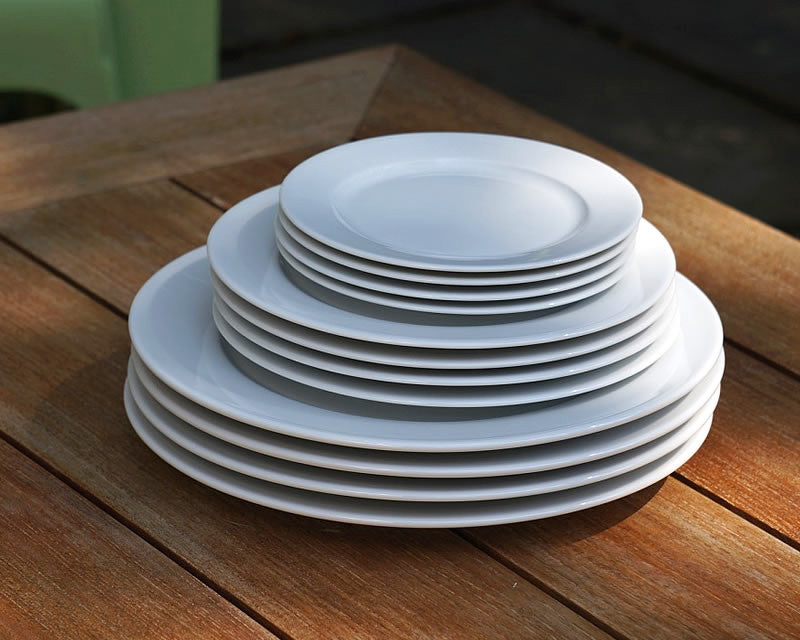 French white dinnerware plates stacked upon one another on a wooden table